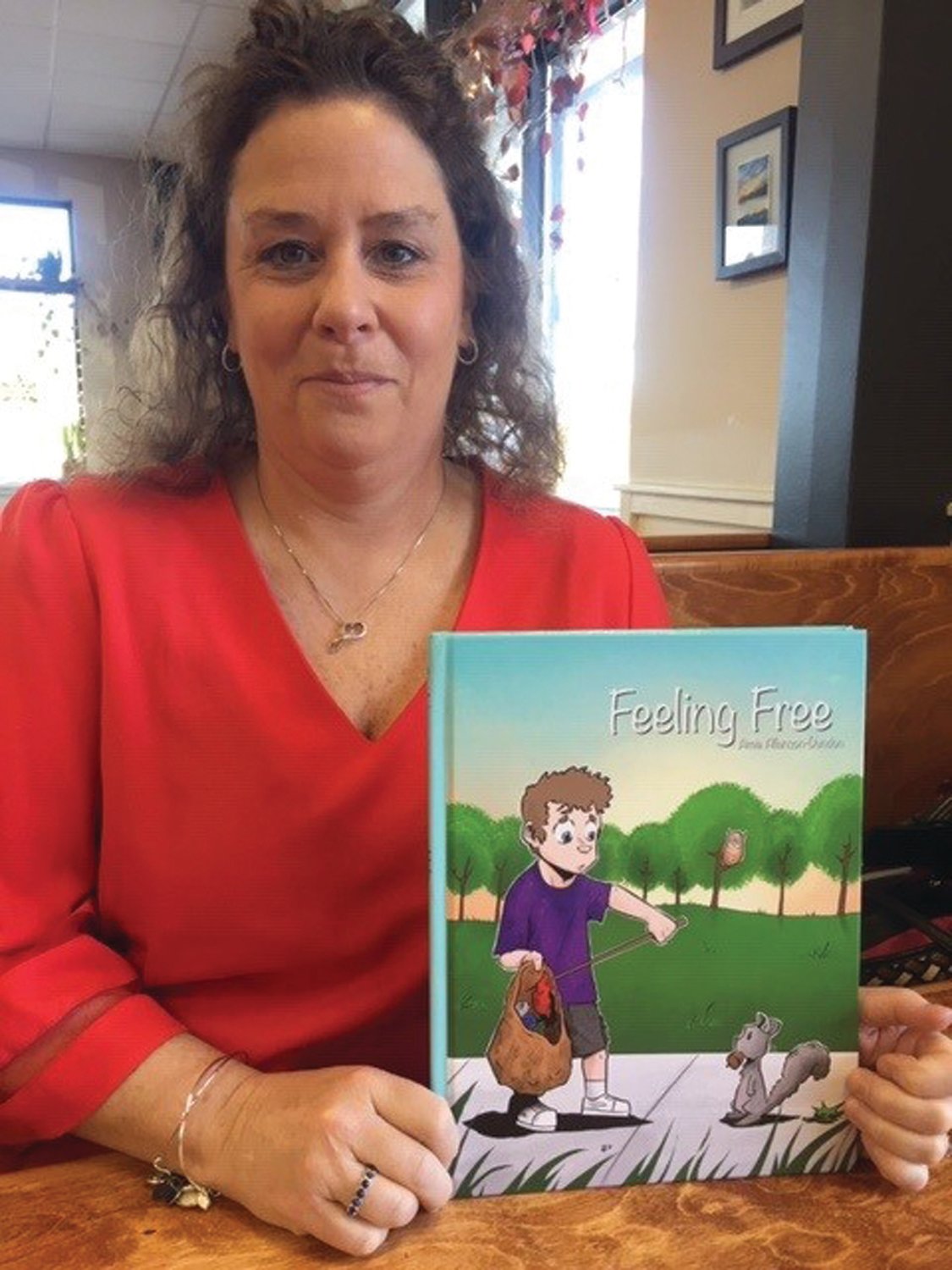 Amie Allanson-Dundon, of Springfield Township, poses with her new book “Feeling Free,” which encourages young people to share their anxieties with others.