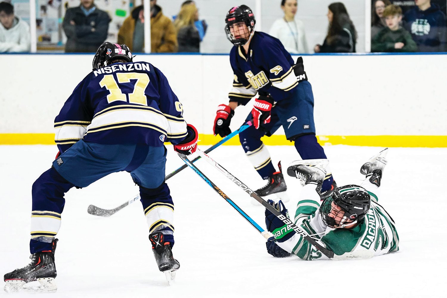 Pennridge’s Shane Dachowski manages to get a pass off despite being checked to the ice in front of CR South’s Gavin Nisenzon.