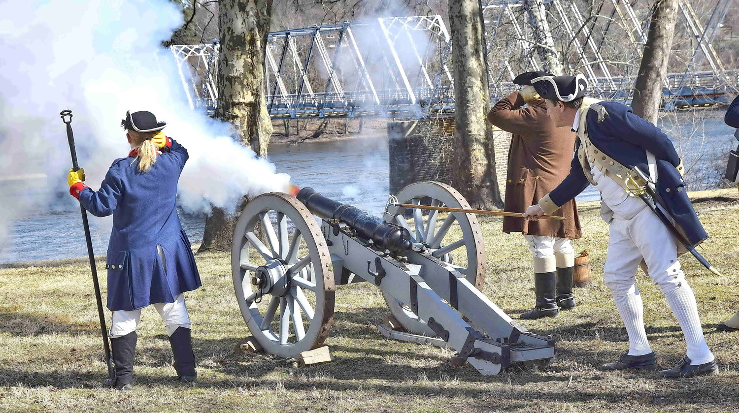 Reenactors portraying Revolutionary War soldiers fire a canon.