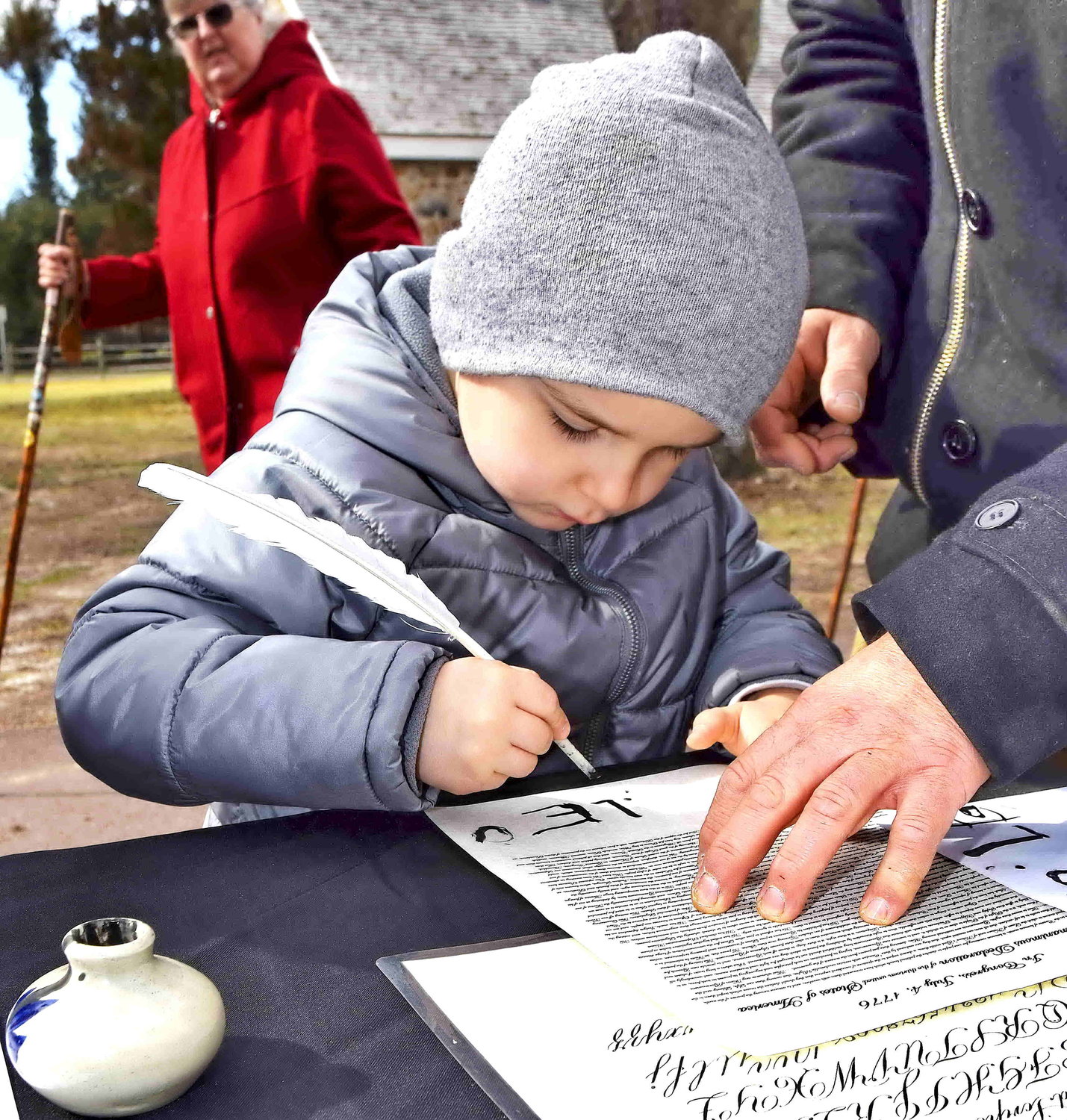 A youngster tries writing with a quill pen.