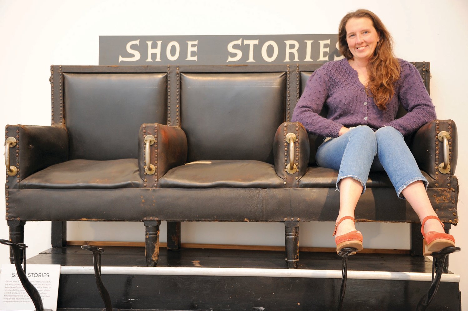 Kate Lambdin sits in a vintage shoe shine chair from “Shoes, A Love Story,” curated by Jill Kearney.