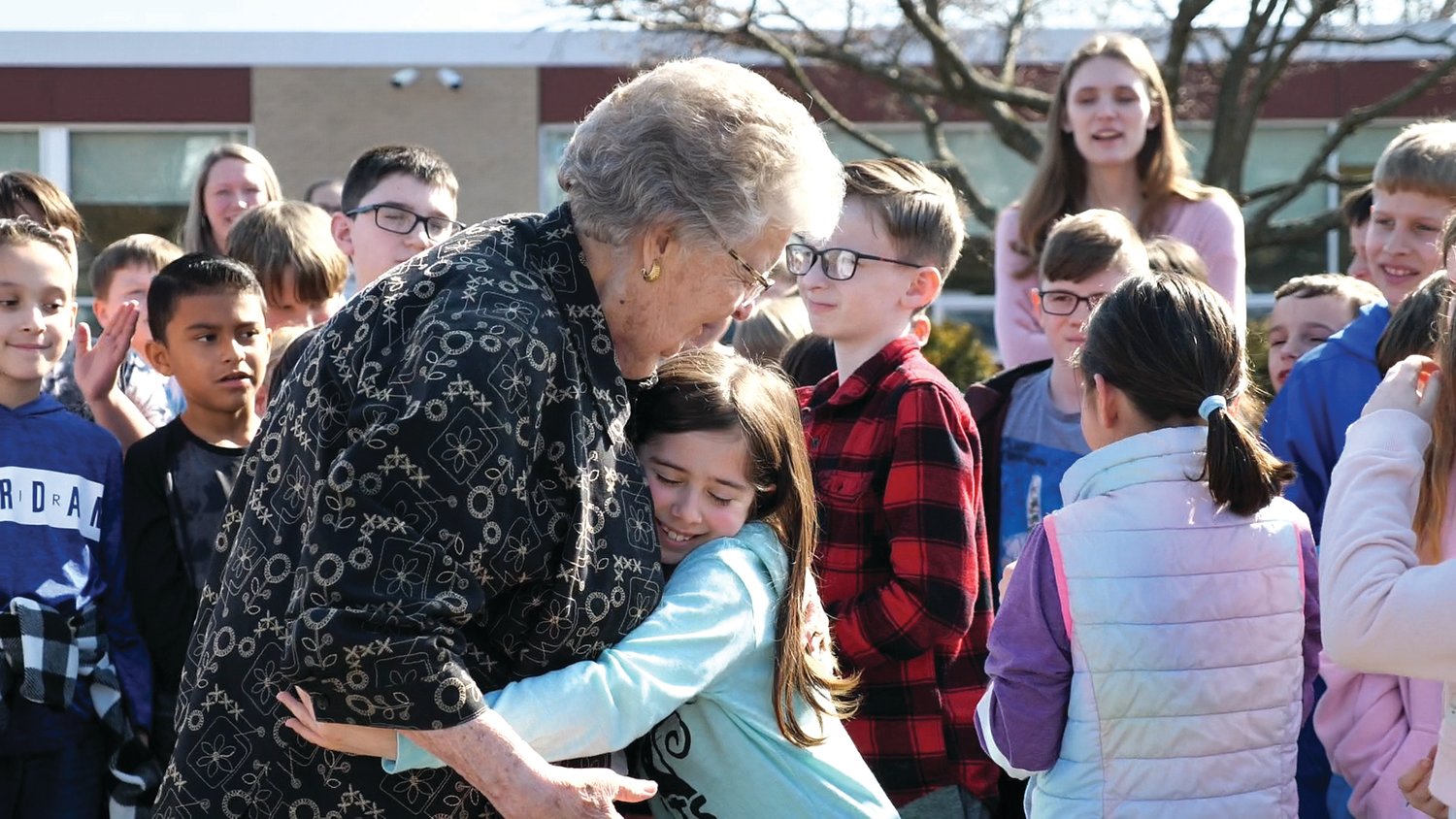 Dr. Patricia A. Guth accepts a hug from a student upon her recent return to the Pennridge Elementary School that bears her name.