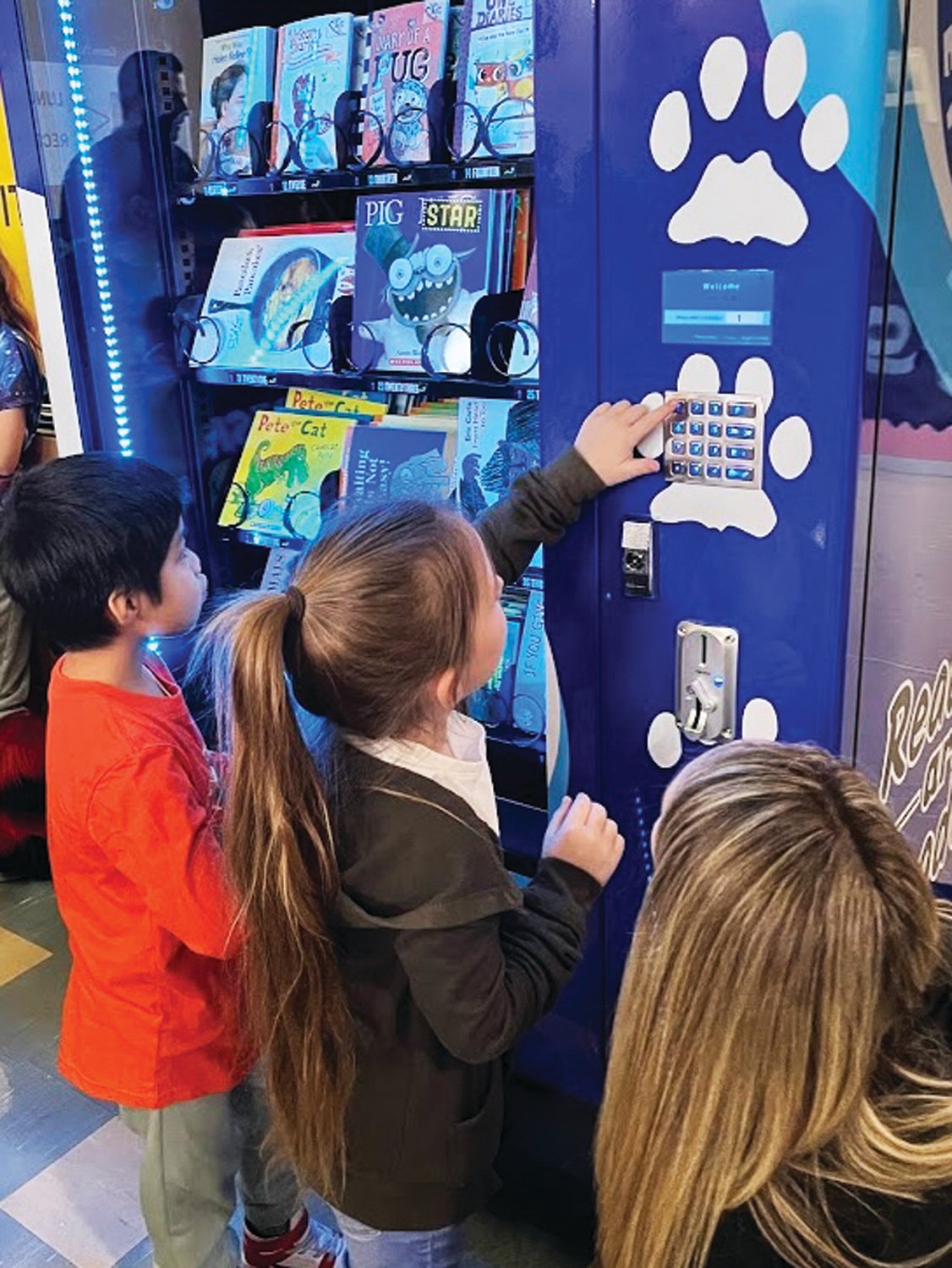 Students use coins they receive for positive behavior to select books from the school's new book vending machine.