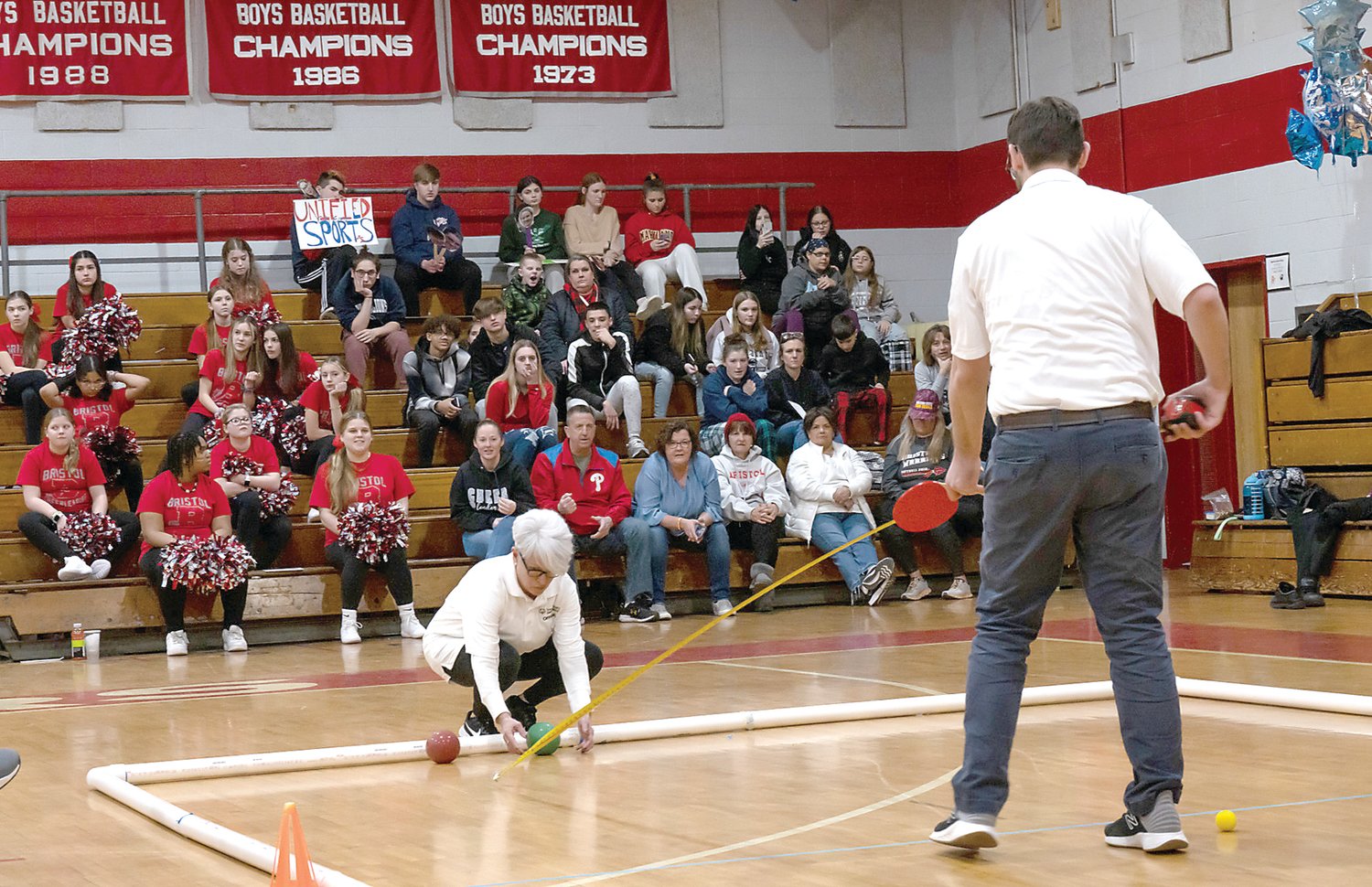 Officials measure the placement of two balls on the court as the crowd awaits the ruling.