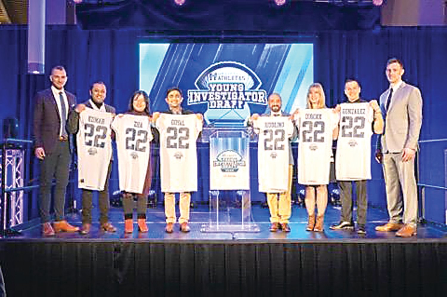 Brett Brackett, right, Uplifting Athletes general manager, and Robert Long, left, executive director, stand with grant recipients at the 2022 Young Investigator Draft.