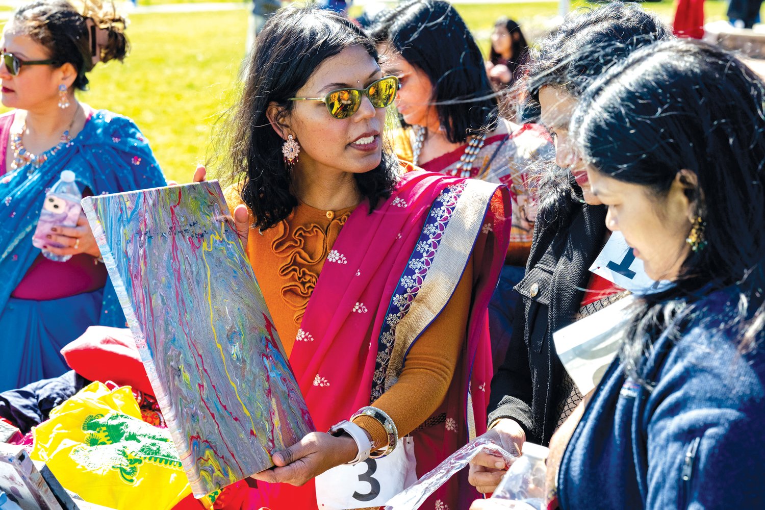 Santosh Yadav holds up a piece of art during a community celebration of culture and unity at Central Park in Doylestown.