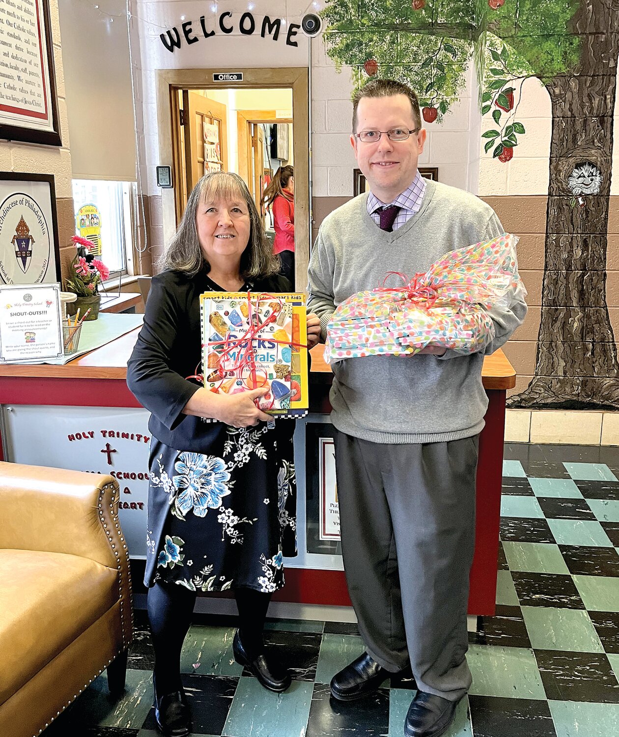 Teacher Kathy Gabriel and Jeffrey McCusker, principal of Holy Trinity School in Morrisville, stand with books donated by members of the Delta Kappa Gamma/Alpha Nu chapter.