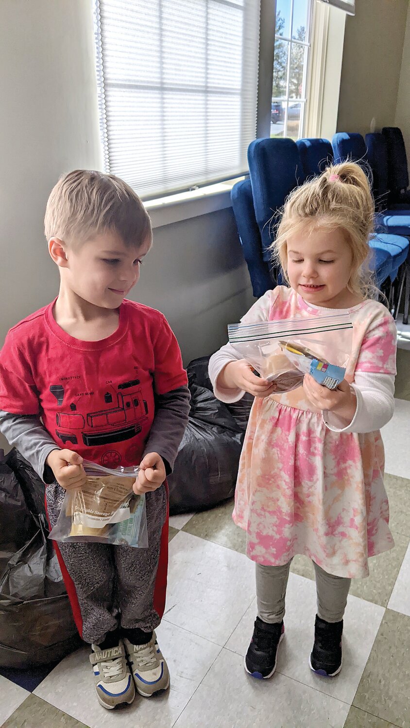 Harrison and Payton from Woodside Christian Preschool hold breakfast snack bags packed for Caring for Friends.