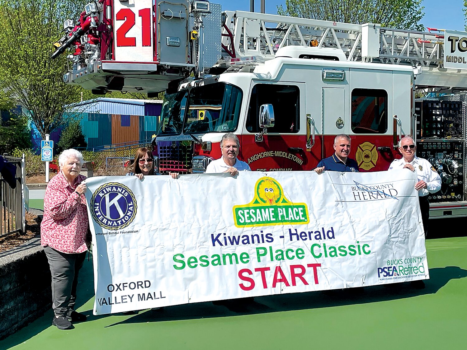 On your mark, get set, go to the 23rd annual Kiwanis-Herald Sesame Place Classic on Sunday, May 21. Included in the festivities will be an appearance by the Langhorne-Middletown Fire Company and its chief, Frank Farry (fourth from left). Also on hand this past Friday at the park to display the Start/Finish banner were, from left, Kiwanis Club’s Dixie Rhodes, Sesame Sprint Director Rose McIver, Bucks County Herald’s Ernie Nocito and Langhorne-Middletown Fire Police’s Larry Harvey.