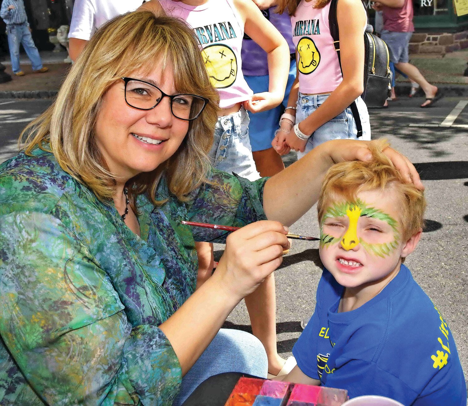 Artist Lanelle Gallagher puts face paint on a young Shad Fest goer.