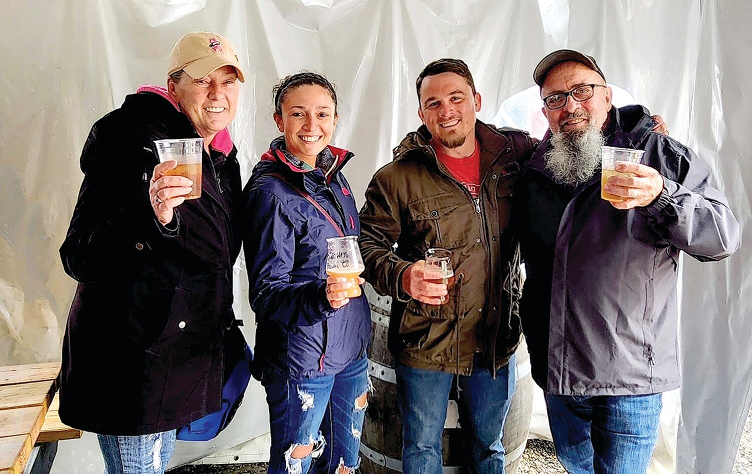 Kimberly Prentiss, newlyweds Kristina and Eric McCann, and Bill Prentiss keep dry under the beer garden tent.