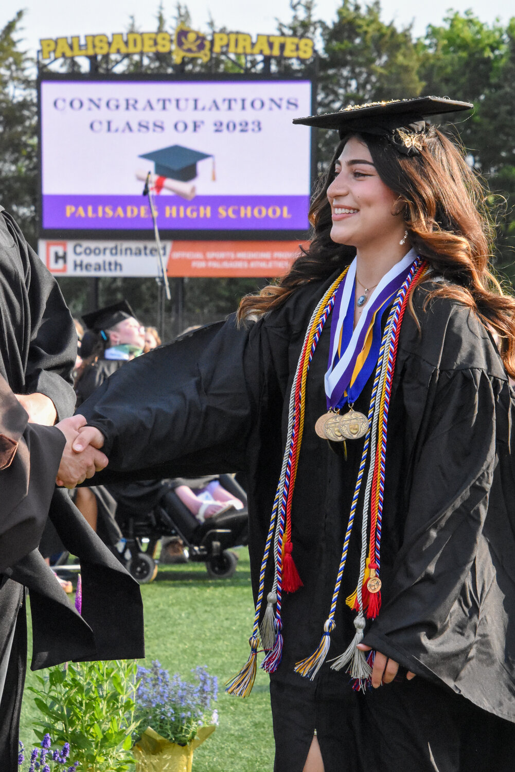 A member of the Palisades High School graduating class accepts a handshake upon picking up her diploma on June 2.
