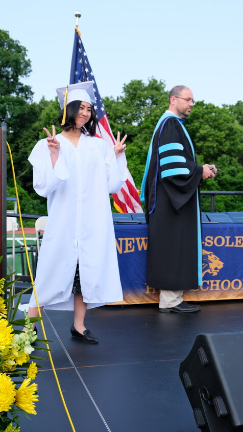 Elize Babia-Ramos flashes a peace sign to her classmates while on stage at the June 13 graduation ceremony.