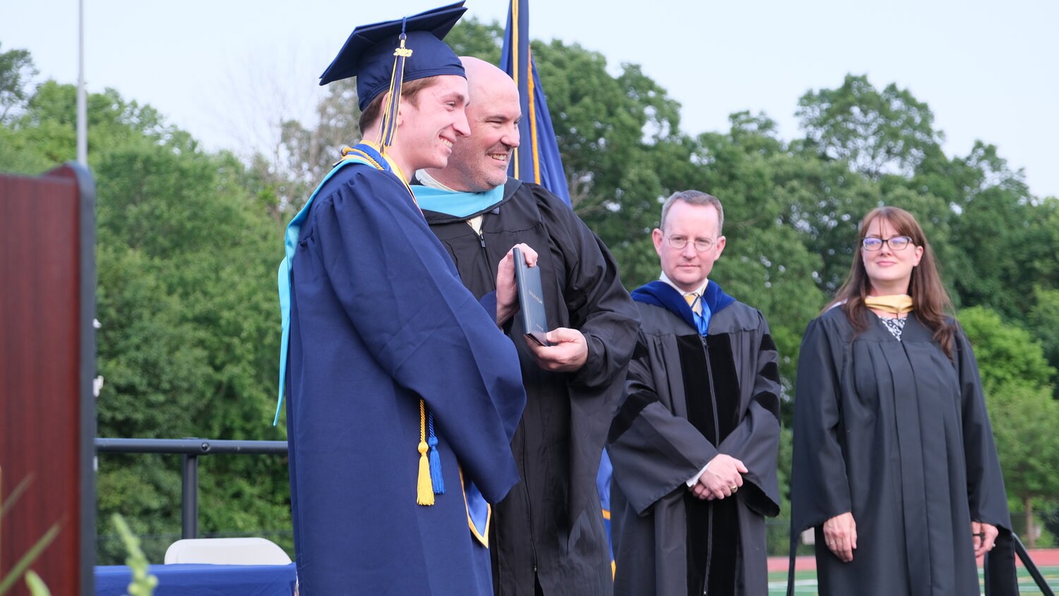 Senior Christopher O’Brien poses for a photograph with High School Principal Patrick Sasse as Superintendent Dr. Charles Lentz and school board president Judeth Finn look on.