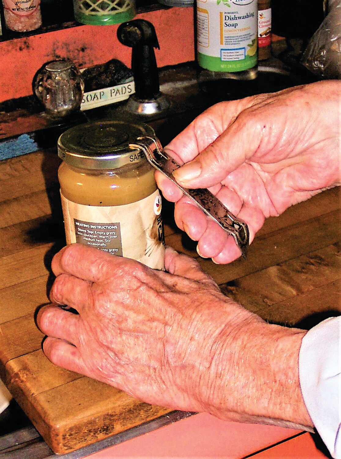 This is how to hold a can opener you're using to break the vacuum seal on a jar.