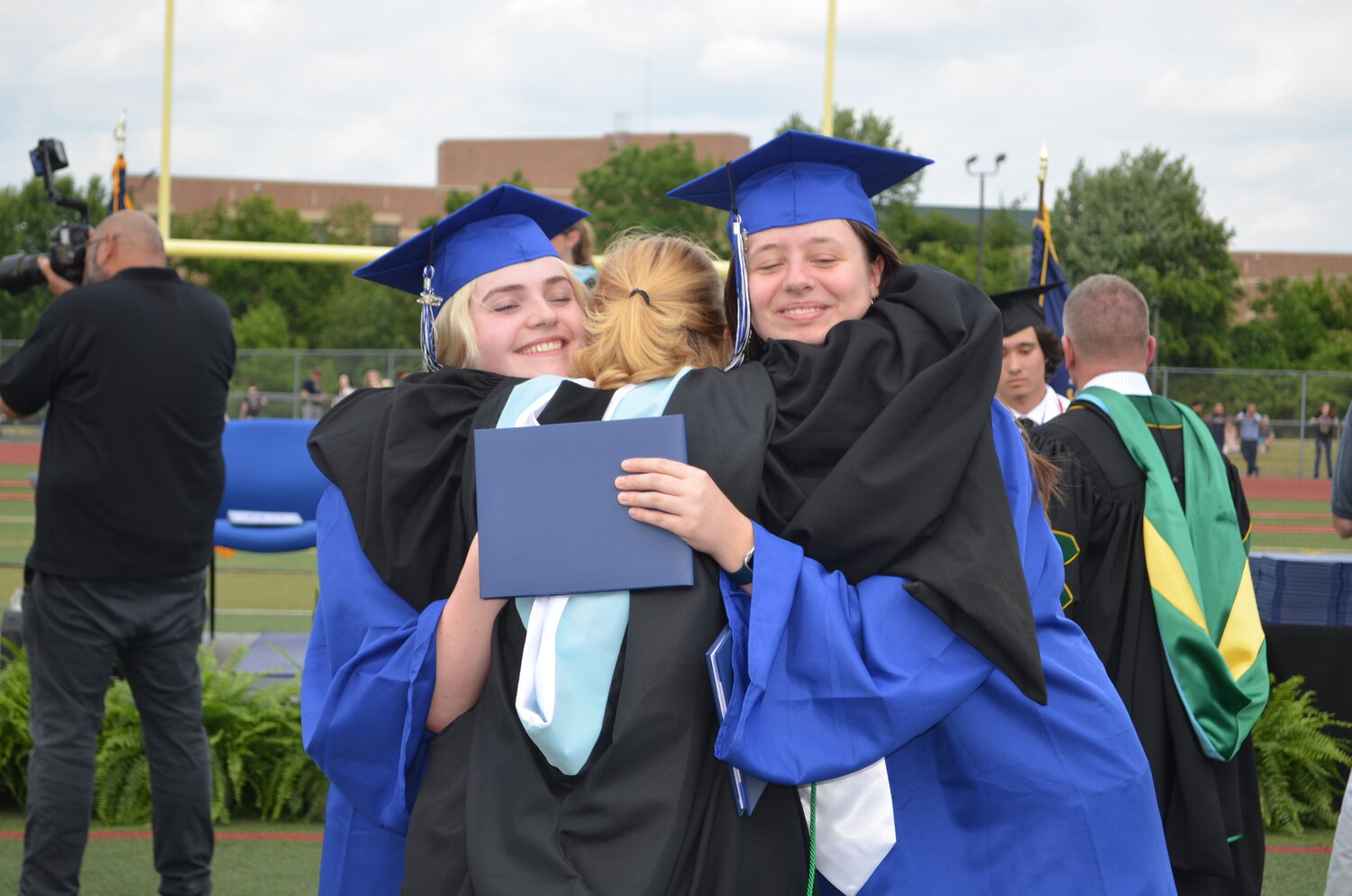 Central Bucks High School South graduates Sarah Capozzoli (left) and Yana Buelens (right) embrace their Titan Forum teacher, Holly Graham.