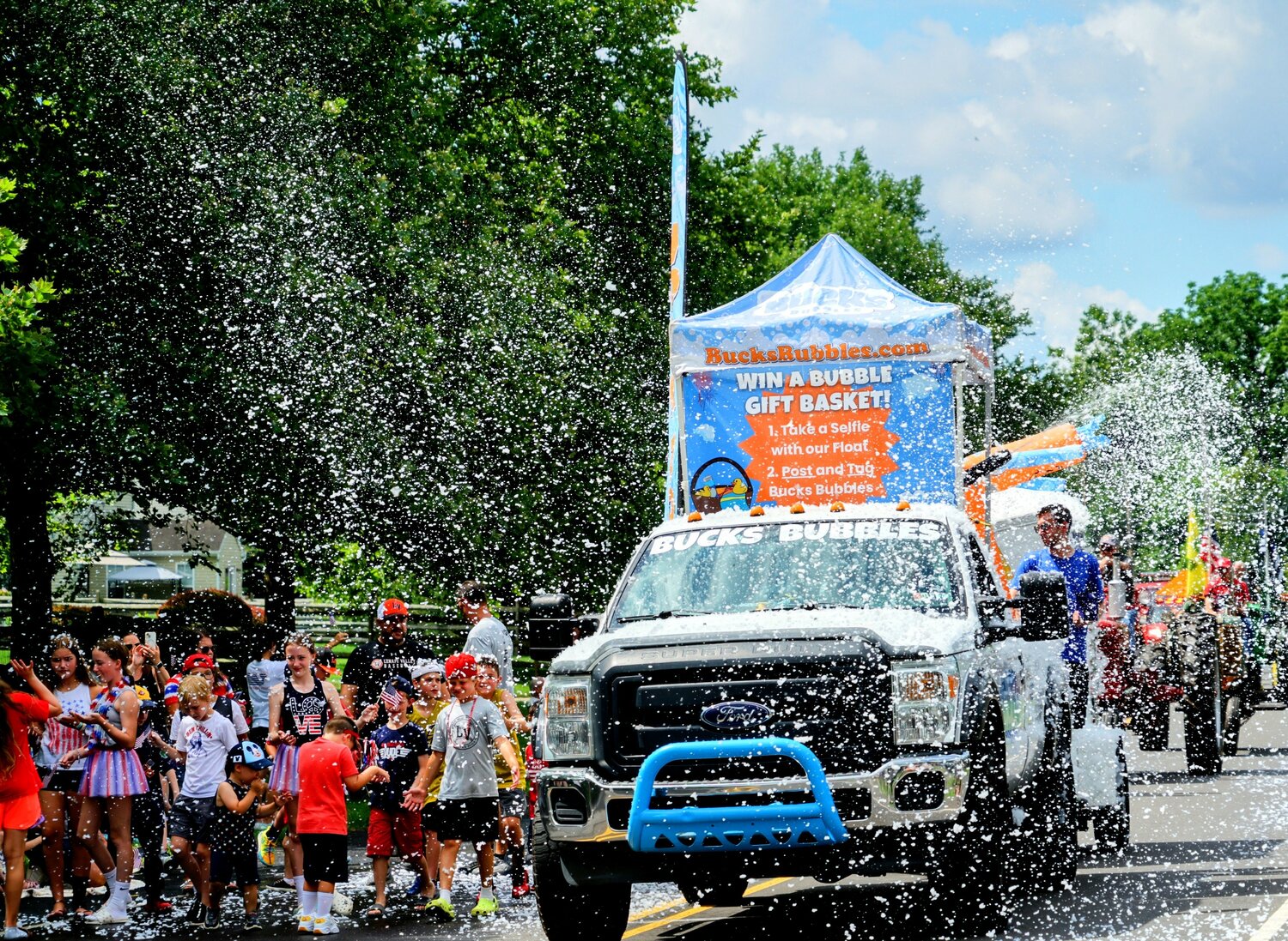 A team from Bucks Bubbles showers parade-goers with suds Tuesday morning during the Tri-Municipal July 4 Parade through parts of Chalfont, New Britain Borough and New Britain Township.