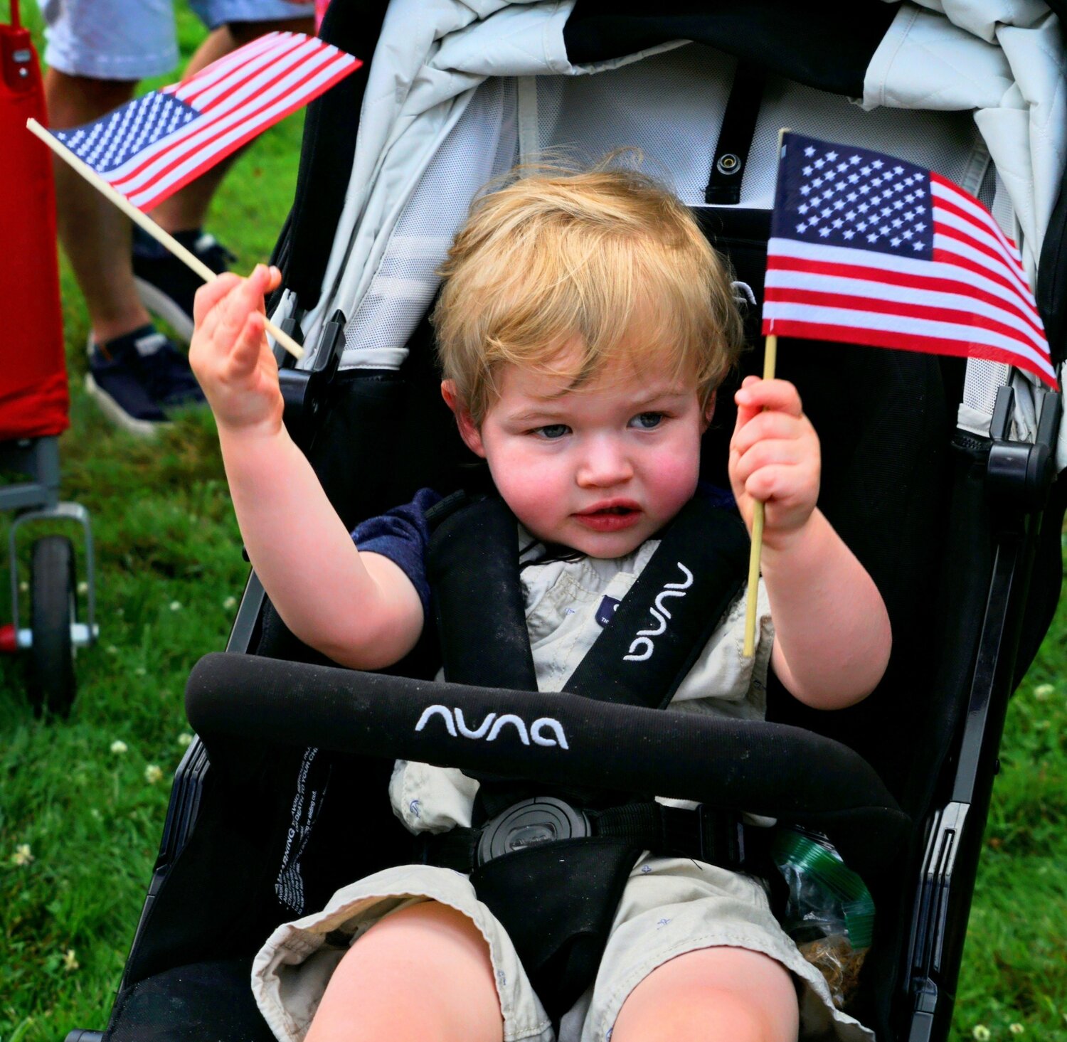 A young parade-goer waves American flags as the Tri-Municipal July 4 Parade passes by Tuesday morning.
