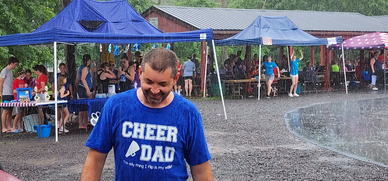 Adam Keller, a Quakertown Cheerleading dad, smiles through the pouring rain Tuesday at the borough’s Fourth of July celebration at Memorial Park.