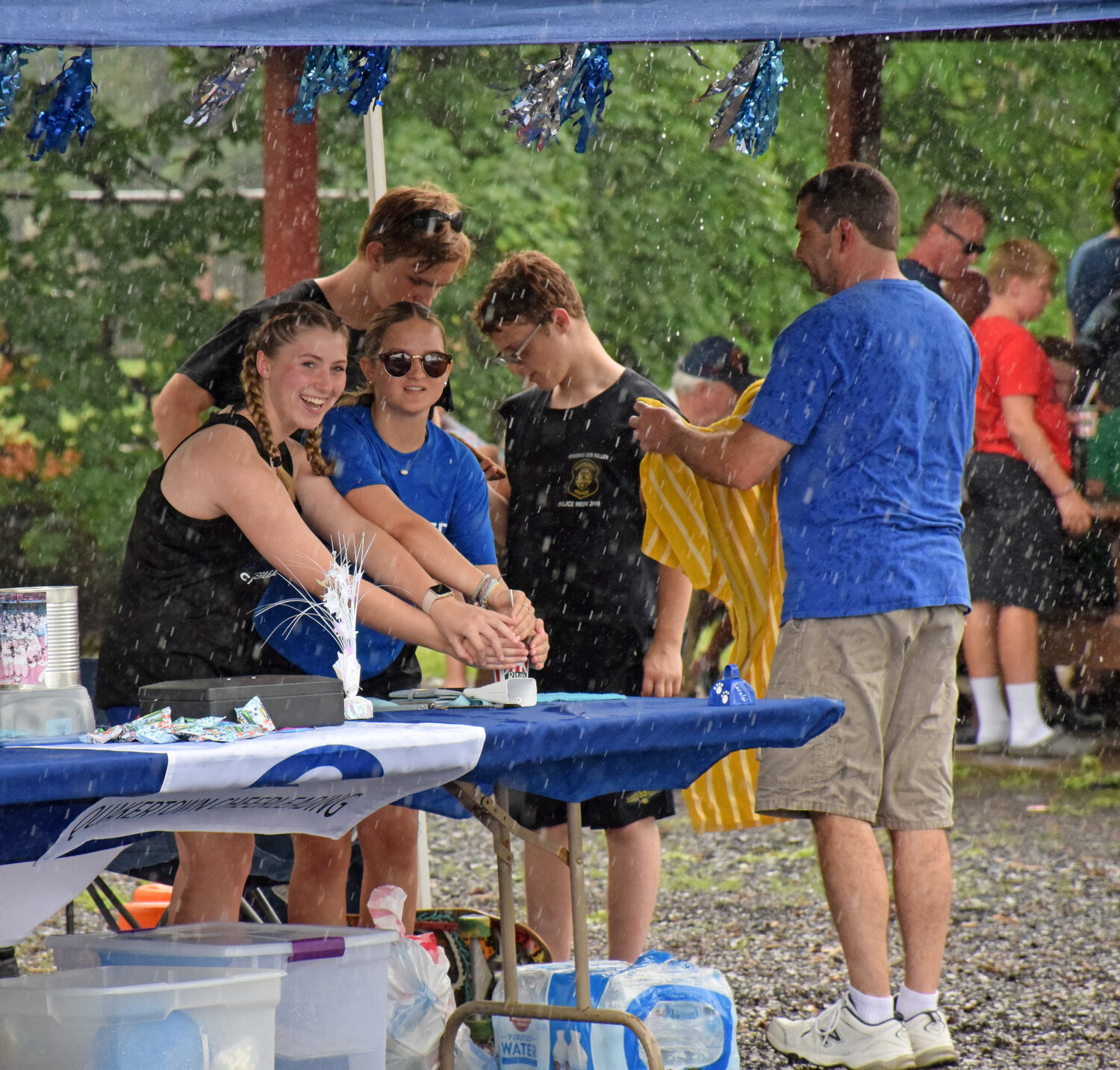 Quakertown Cheerleaders Alyssa Fonda and Alexis Austin protect their Rita’s Water Ice during the heavy downpours at Quakertown Community Day Tuesday.
