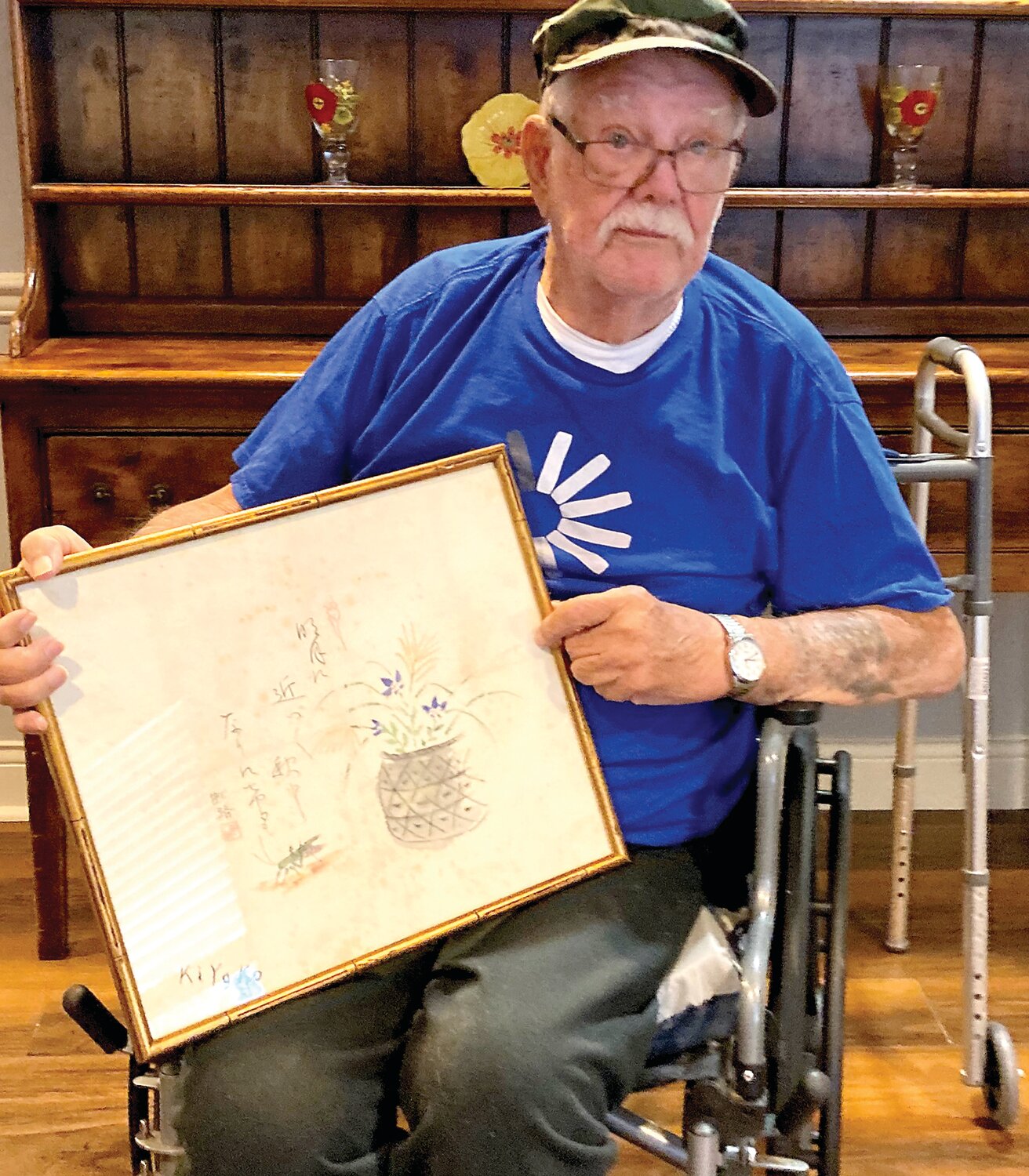John Brenton, a U.S. Army WWII veteran, holds a piece of artwork in which a Japanese captured soldier secretly returned money stolen from American Marines killed in combat. Brenton served in Saipan, in the western Pacific, as an infantry soldier from 1943 to 1945.