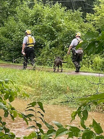 Rescuers walk along the canal towpath Sunday afternoon in search of those who went missing Saturday in a flash flood.