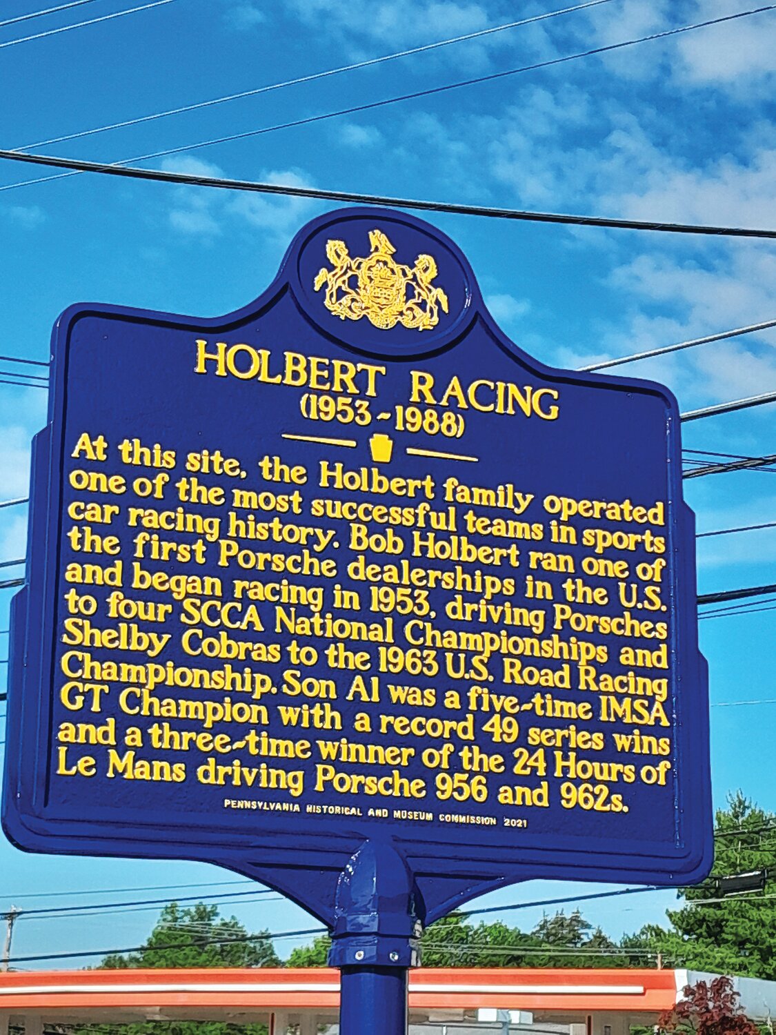 A blue and gold plaque near the intersection of 611 and Bristol Road pays homage to the Holbert family racing legacy.