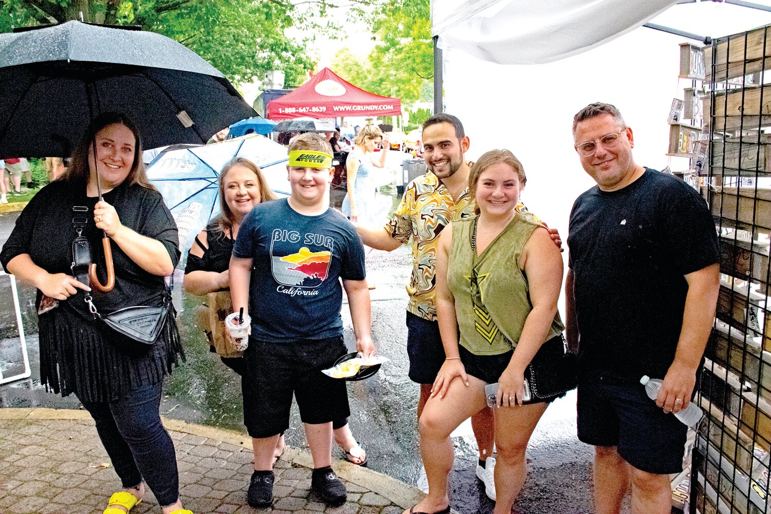 The Mullers of Bucks County and the Bronshtein family, visiting from Florida, take cover from the downpour during the car show.