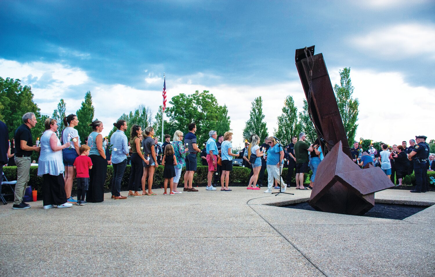 During Sunday’s vigil at the Garden of Reflection, attendees stand in line to place flowers in front of torches dedicated to the victims of the July 15 flash floods in Upper Makefield.