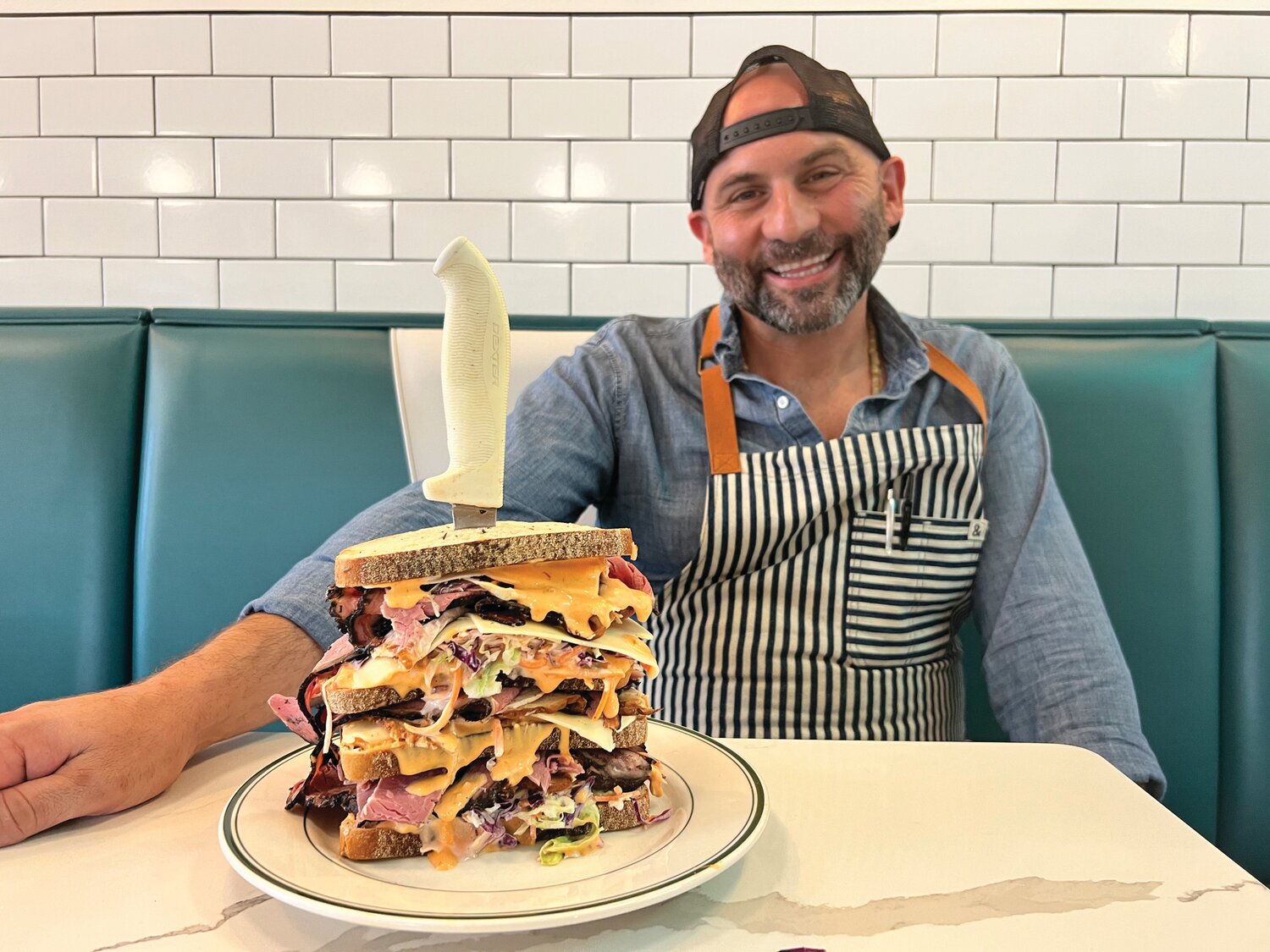 Borscht Belt chef and co-owner Nick Liberato with The Meshuggenah, an over-sized version of the deli’s Kellerman’s Favorite being offered through the month of August, which is National Sandwich Month.