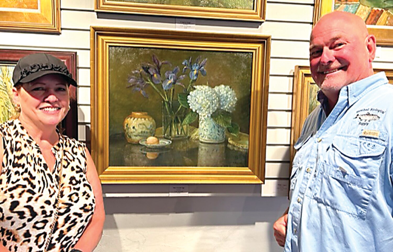 Deb and Bob Kreilick admire Dot Bunn’s painting of Willi Singleton’s pottery and irises from Deb’s garden.