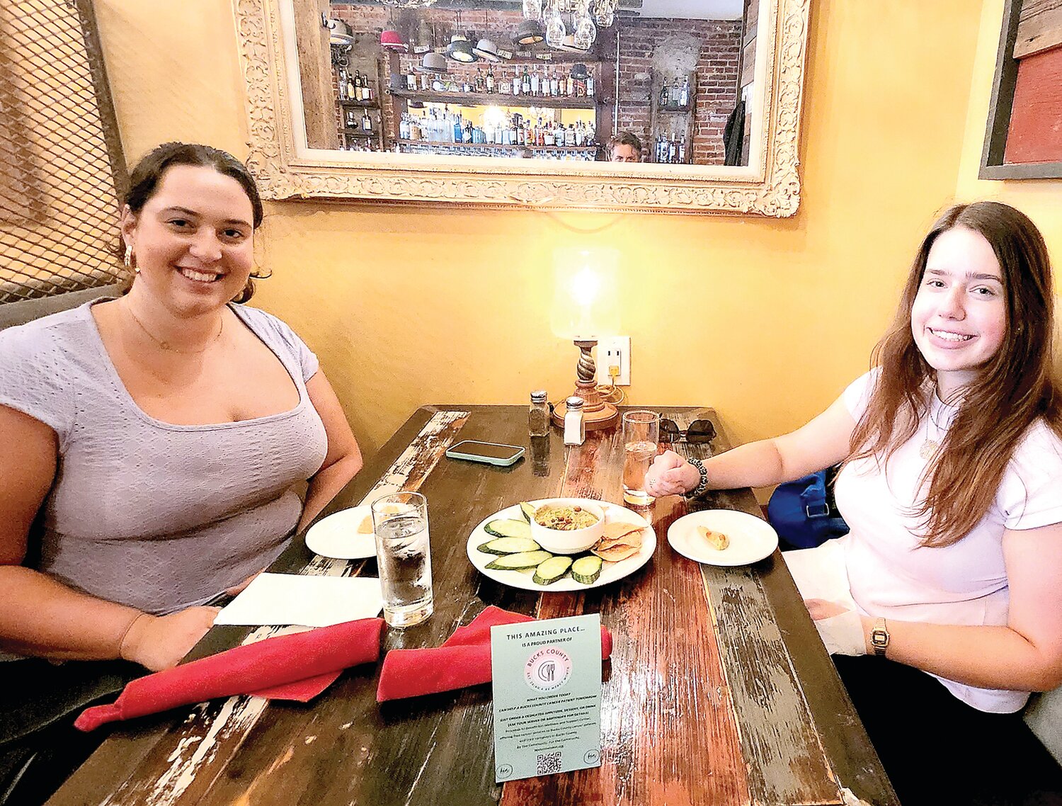 Olivia, left, and Brooke, right, enjoy a Hummus Verde Plate at The Hattery in Doylestown. The Hattery is one of 31 restaurants and bars participting in Bucks County Eat, Drink an Be Merry Month to benefit Kin Wellness and Support Center.