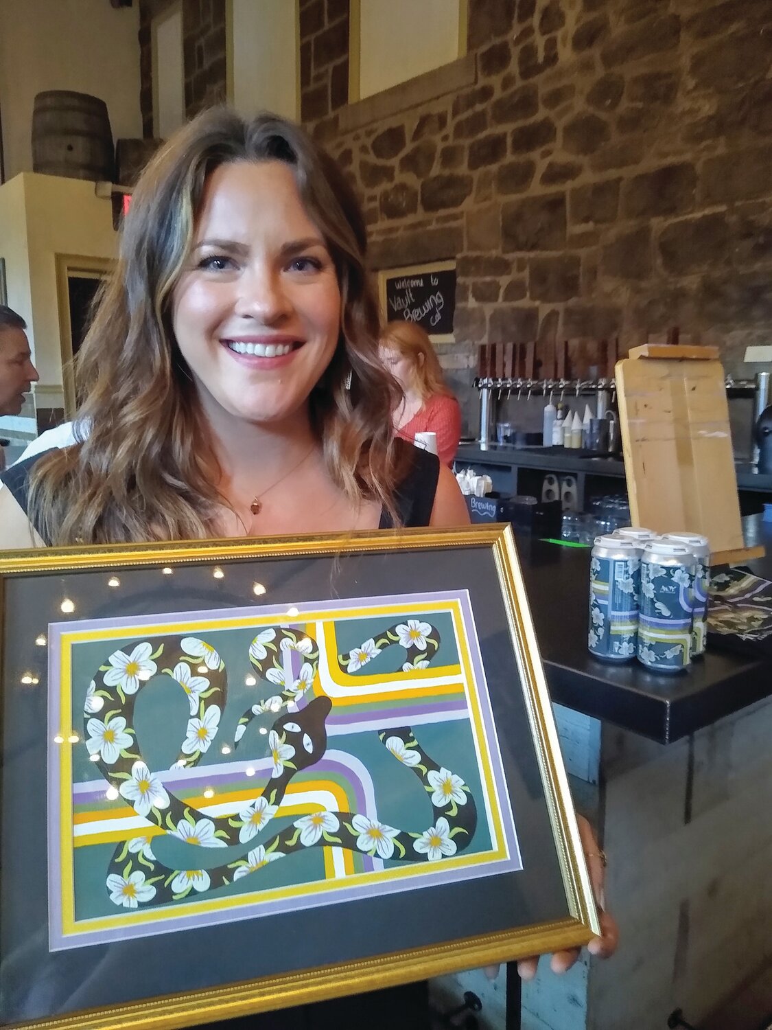 AOY Art Center member artist Amanda Brun of Yardley holds her winning entry, "Snake and Swirls," for the Craft Beer Can Design Contest for Vault Brewing’s limited edition of its Teller Pilsner.