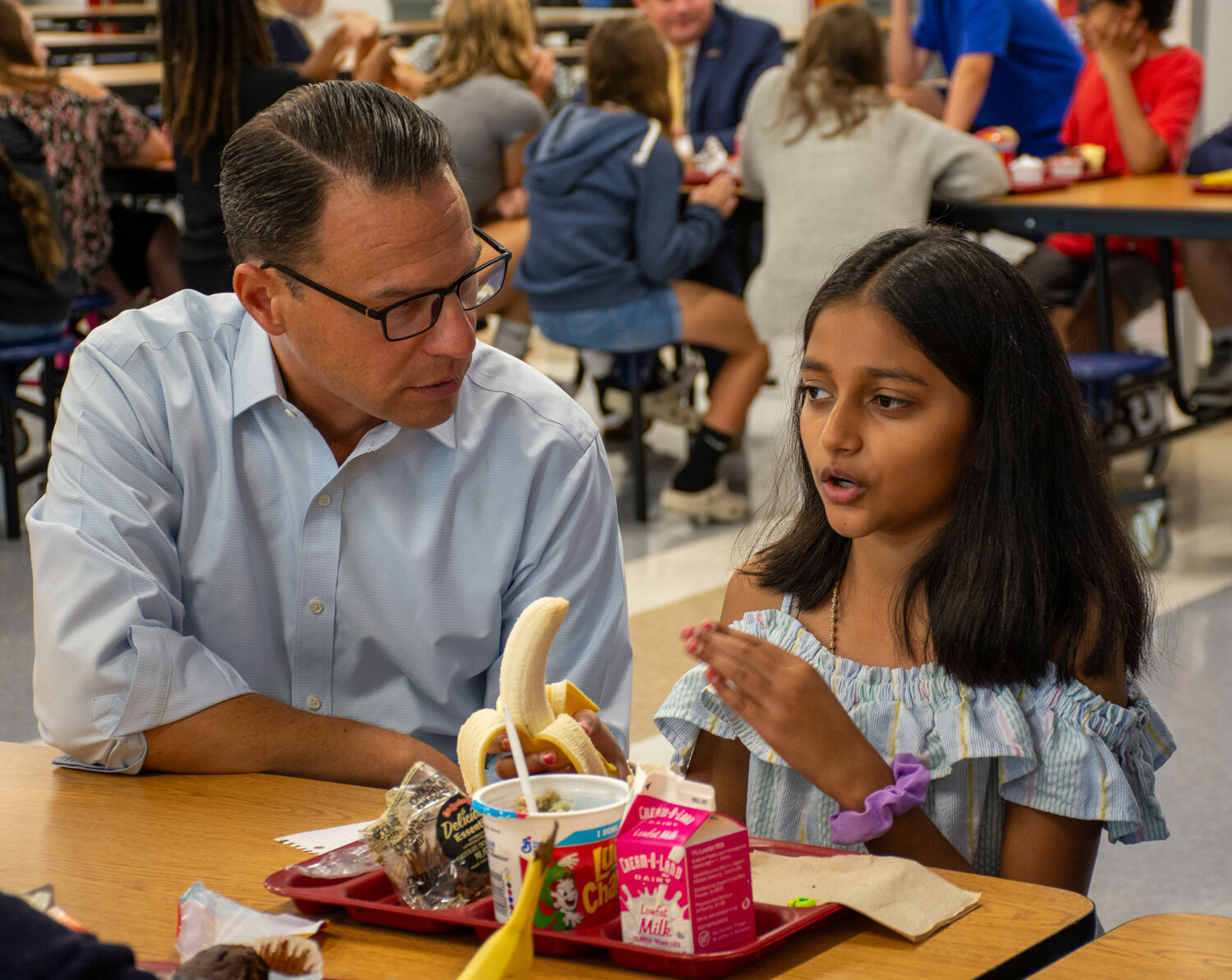 Pennsylvania Governor Josh Shapiro listens as a Maple Point Middle School student Aarushi Patel, grade 5, talks Friday morning during breakfast in the cafeteria of the Neshaminy School District school.