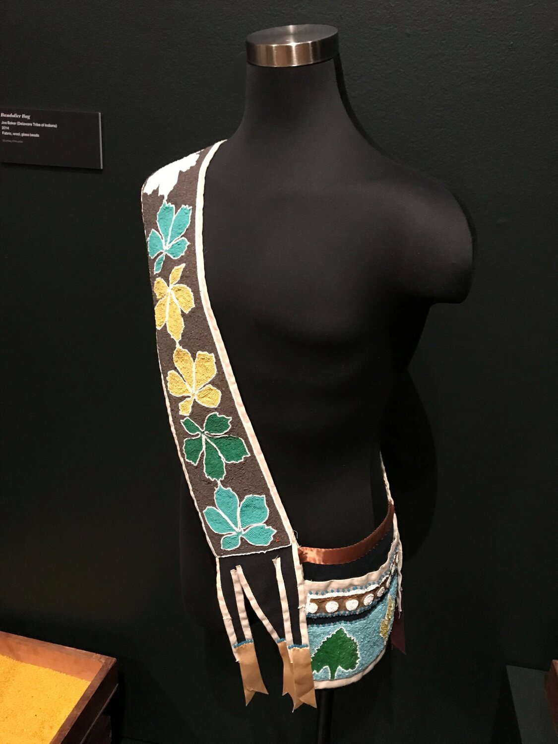 Lenape artist Joe Baker, of the Delaware Tribe of Indians, created this Bandolier Bag out of fabric, wool and glass beads.