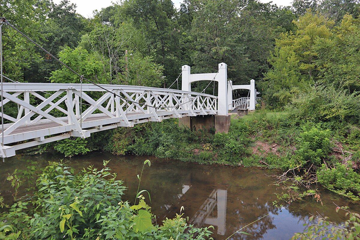 Twin Roebling suspension bridges span the creek that runs through the Lake Lenape Park today.