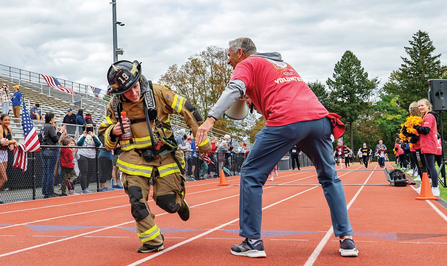 A volunteer firefighter gets a low-five from a volunteer.
