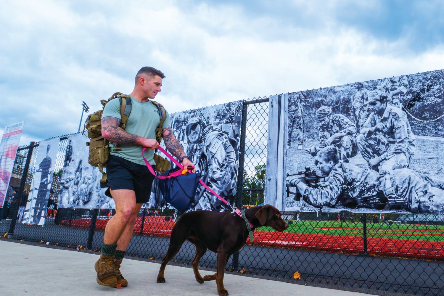 An attendee of the 9/11 Heroes Run Sunday at War Memorial Stadium at Central Bucks West High School walks past a collection of images depicting American troops.