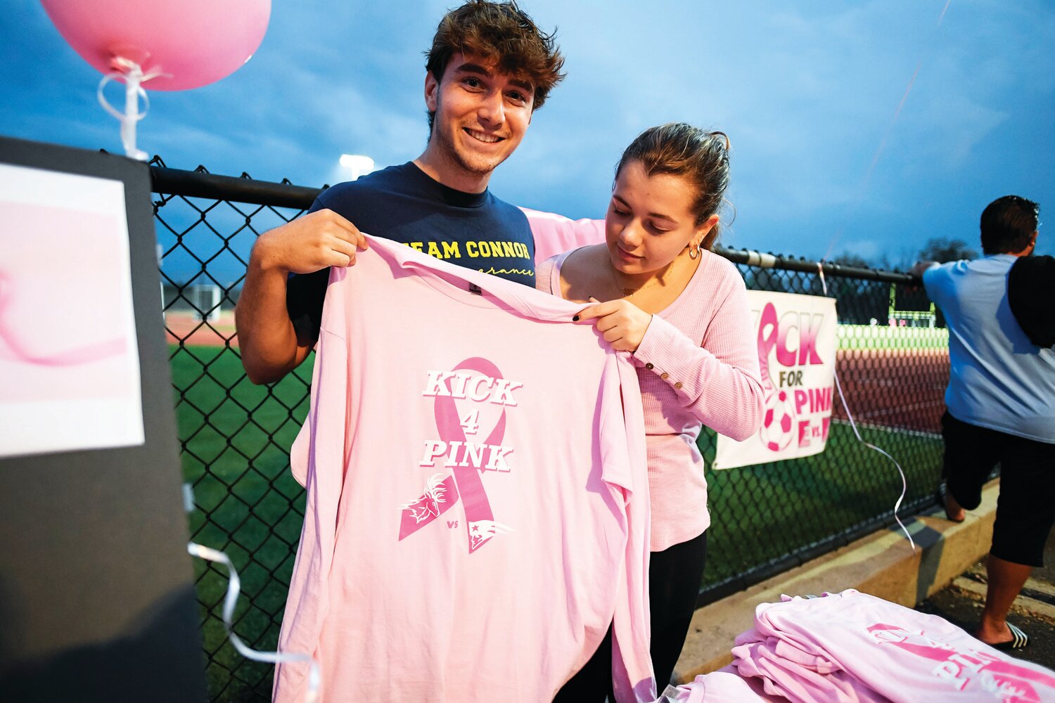 Michael Steitz and Rylee Decker, both from CB East, volunteered for the night to help with the shirt sales. Players from both schools wore the shirt before the start of both games in support of breast cancer awareness month.