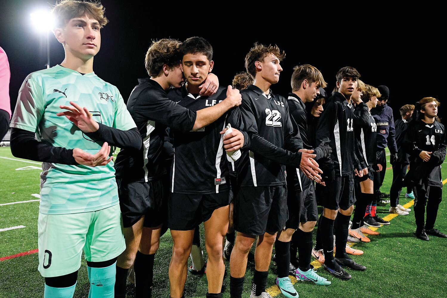 Faith Christian’s Lincoln Waltenbaugh hugs Ben Goodrich during the District One Class A medal presentation.