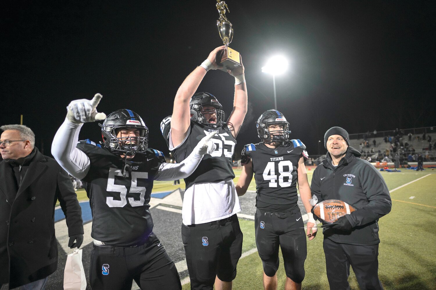 Central Bucks South captains Rolan Hess, Collin Goetter and Sean Moskowitz, and coach Tom Hetrick celebrate after getting the championship trophy.