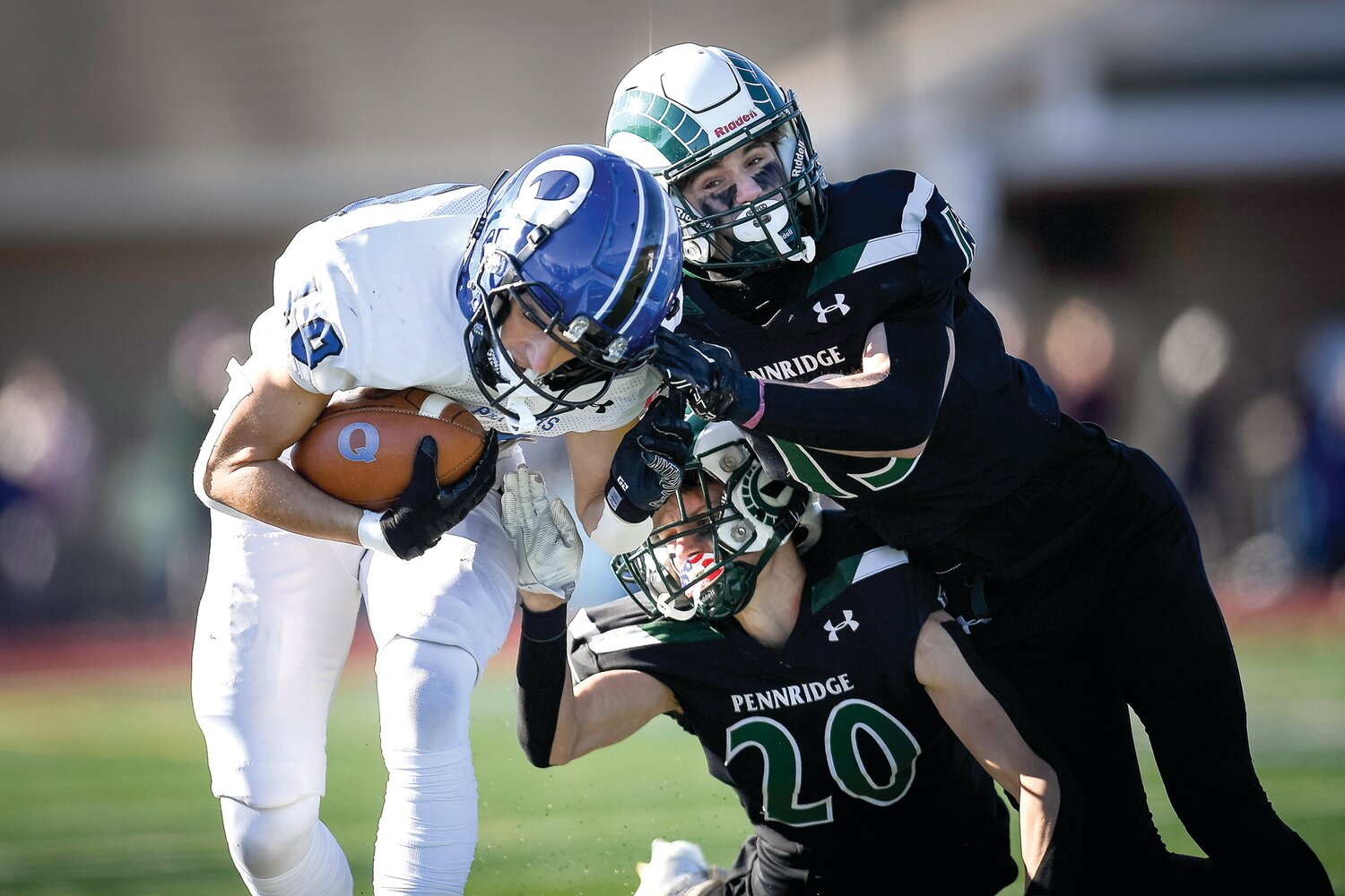 Quakertown’s Aiden Burgy is driven out of bounds after a pass completion in the first quarter by Pennridge’s Joe Hamburger, left, and Chase Marshall, right.