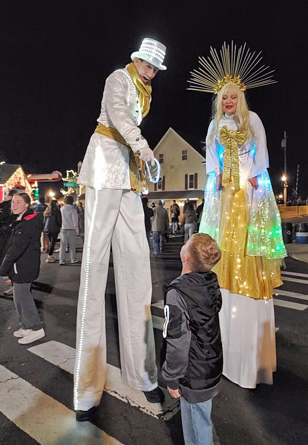 Andrew Scharff, a.k.a. Mister Legs, and Hannah Pinkos, of Skylark Circus Arts, gives a tree-lighting ceremony attendee two people to look up to.