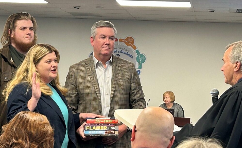 Karen Smith places her hand on a stack of controversial books as she takes the oath of office as a Central Bucks School Board member. Smith’s husband Peter held the books, as Smith’s son Alex Smith, looked on.