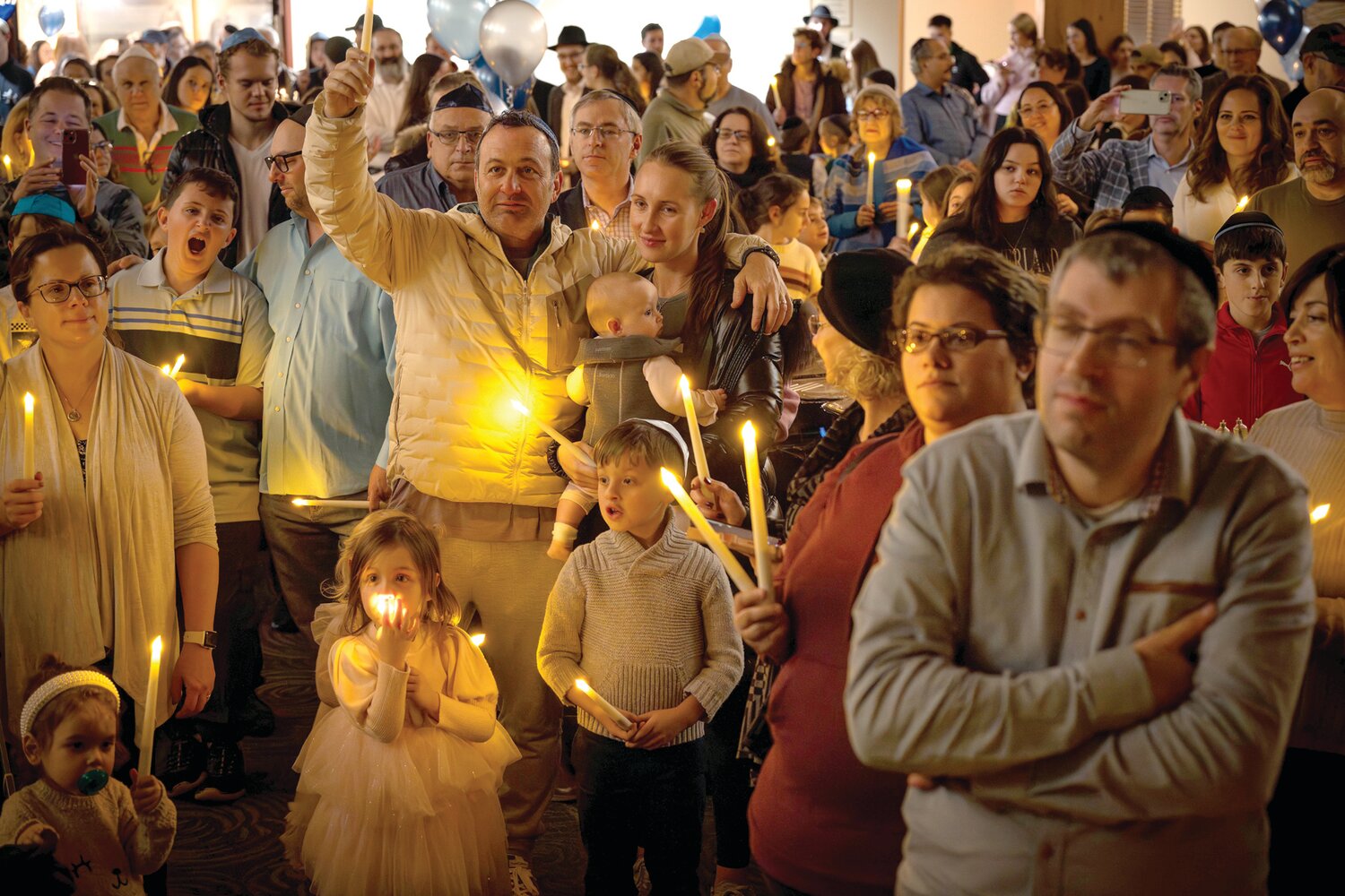 The crowd holds candles during Sunday’s Family Chanukah Celebration at the Glazier Jewish Center in Newtown.