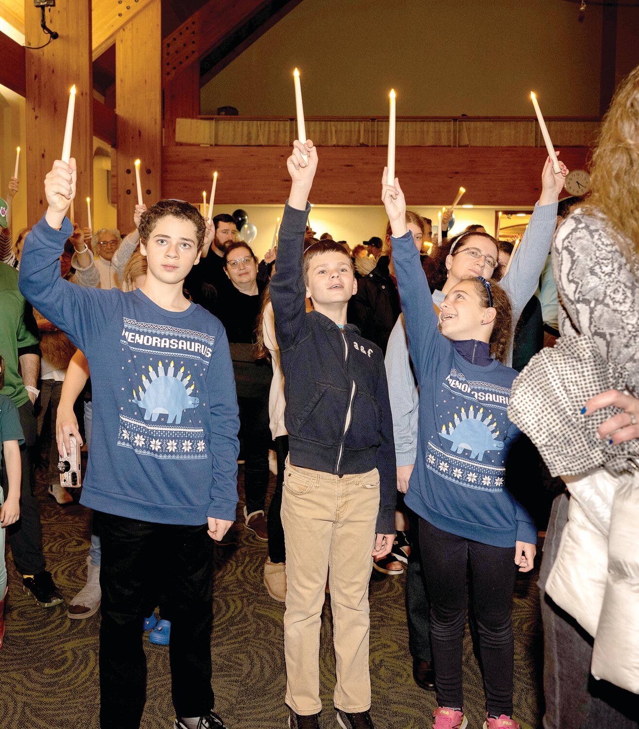 Young people lift their candles at the Family Chanukah Celebration in Newtown.