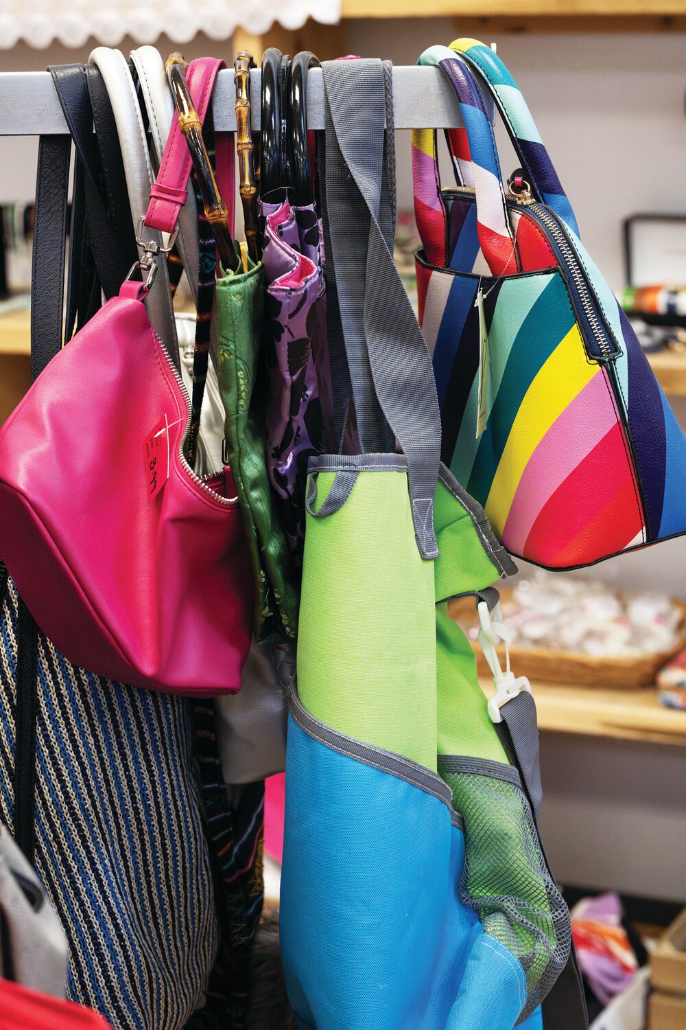 Bags of various colors and styles hang on a rack waiting to be bought at Worthwhile Wear.