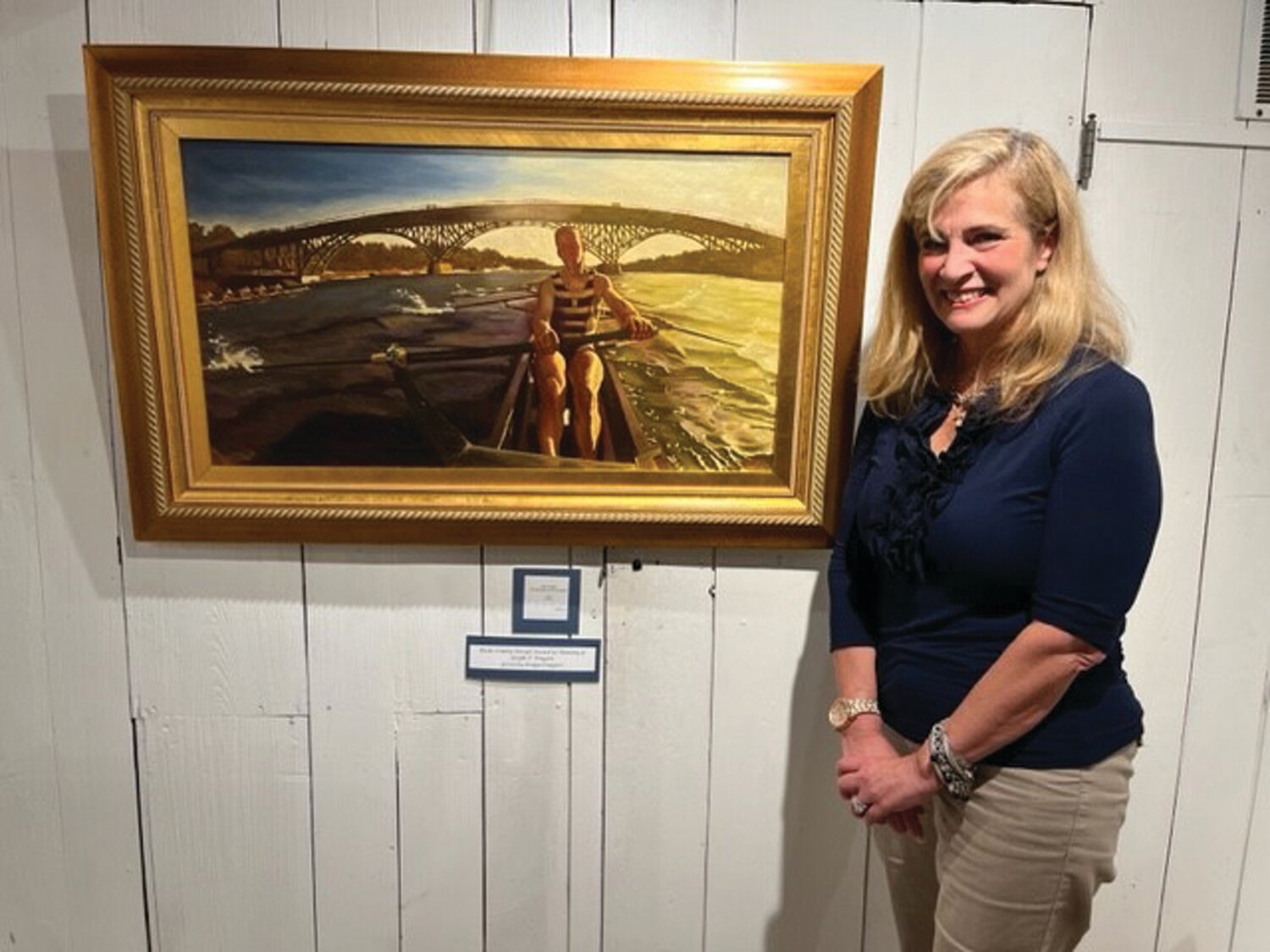Kate Quinn Wright poses with her oil painting, “Fall Rowing on the Schuylkill.” She won the Bucks County Herald Award at the Phillips Mill Art Show.