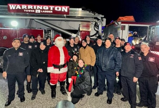 Kristen Masciantonio and her daughter Gianna Grace, center, stand with Santa Claus and members of the Warrington Township Fire Company on Dec. 19 at the 10th annual Fire Truck Santa visit.