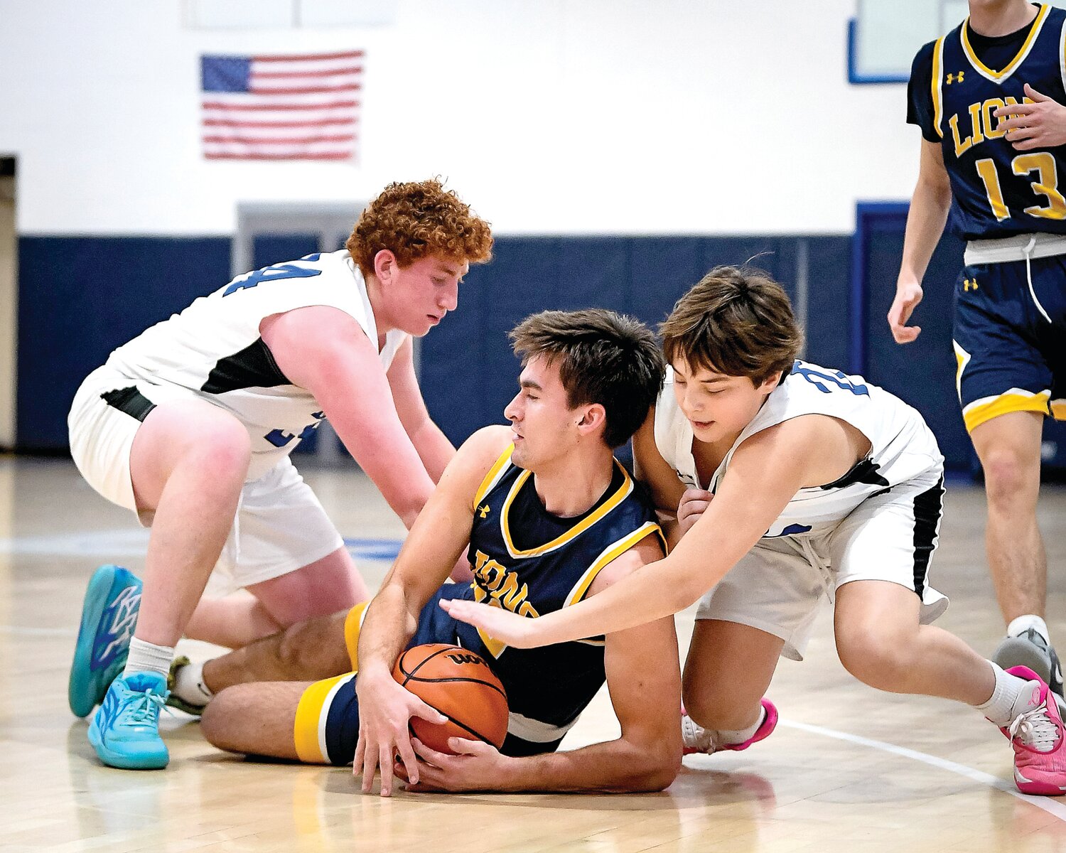 New Hope-Solebury’s Dylan Fitzgerald dives to gather a loose ball in between Jack M. Barrack Hebrew Academy’s Jonah Thomas and Max Shapiro.